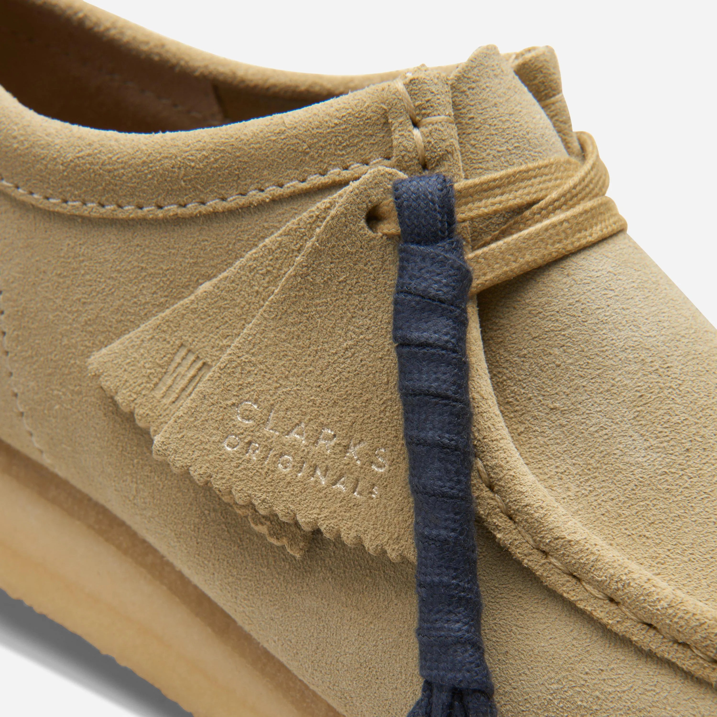 Close up on the waxed laces, premium maple suede texture, and the two tonal Clarks Originals fobs.