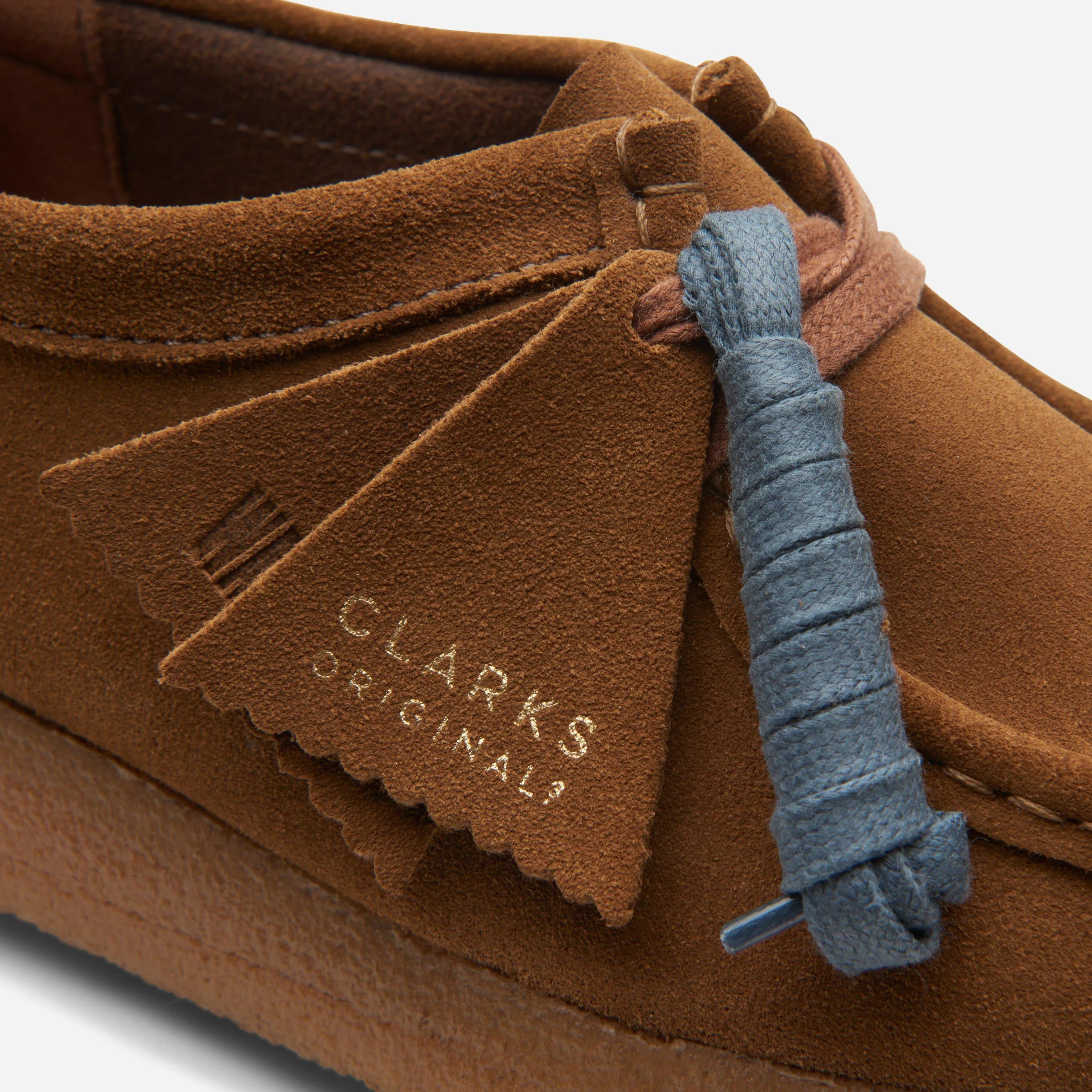 Gros plan sur le daim premium Cola, les lacets cirés et les fobs Clarks.