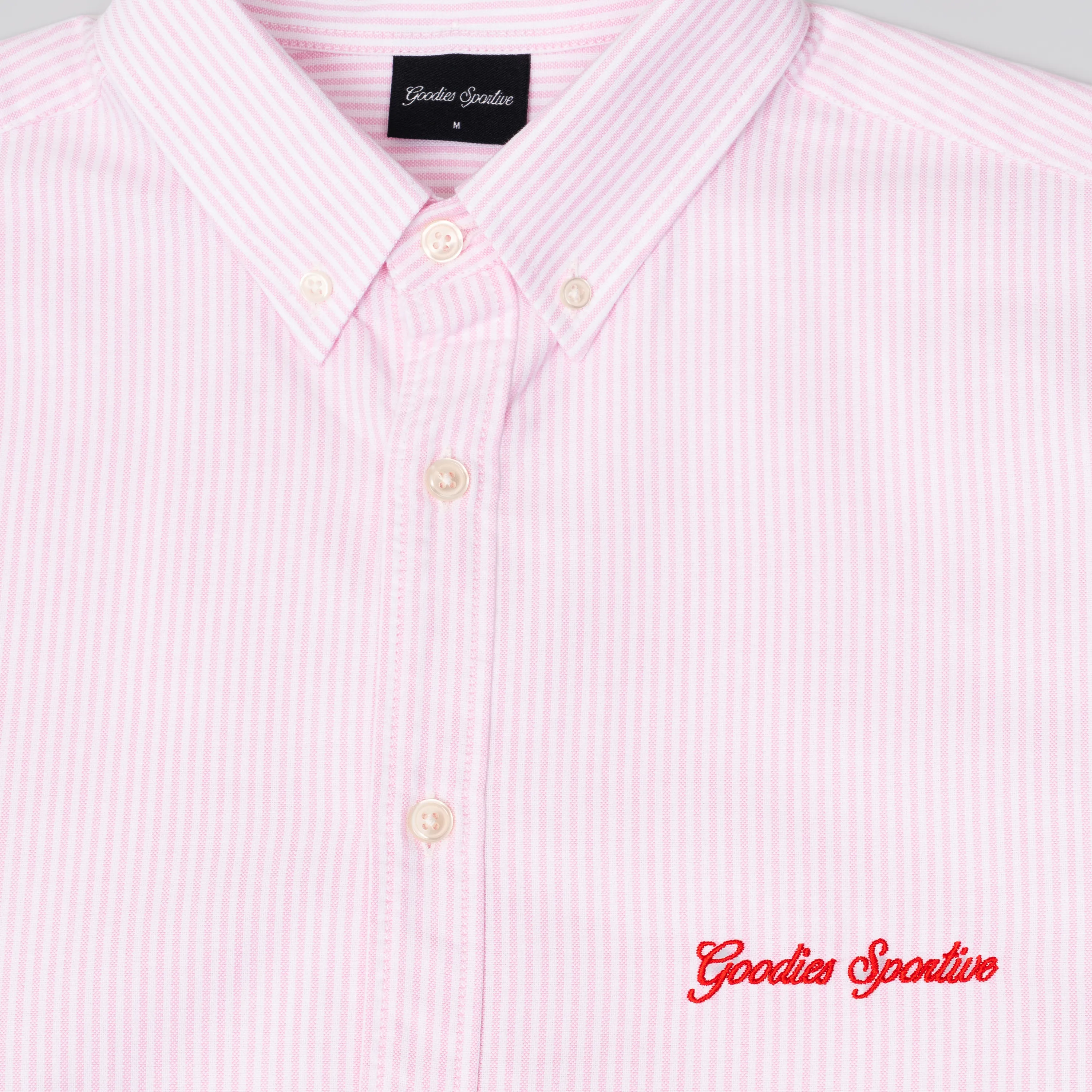 Close-up on the button-down collar and red script embroidery on striped fabric.