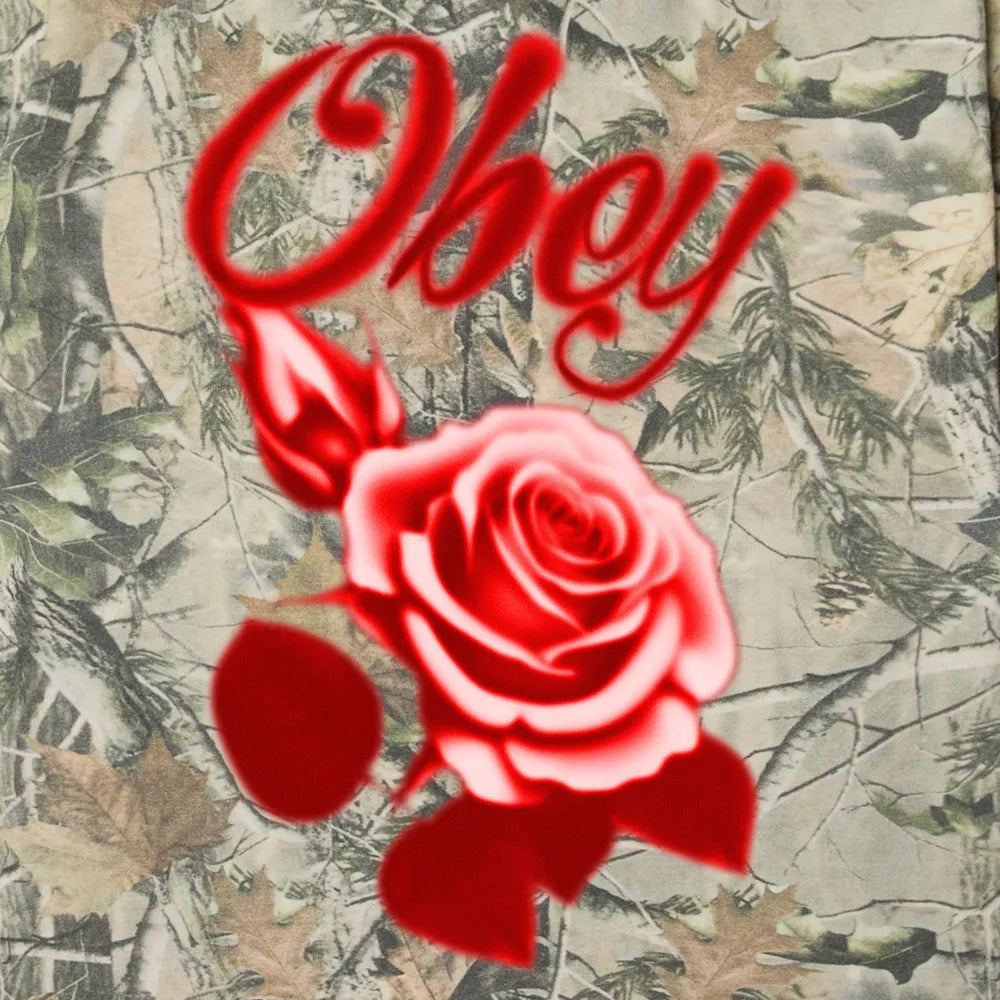 Détail de l'illustration vibrante de la rose rouge et du lettrage Obey style airbrush sur le motif Leaf Camo.