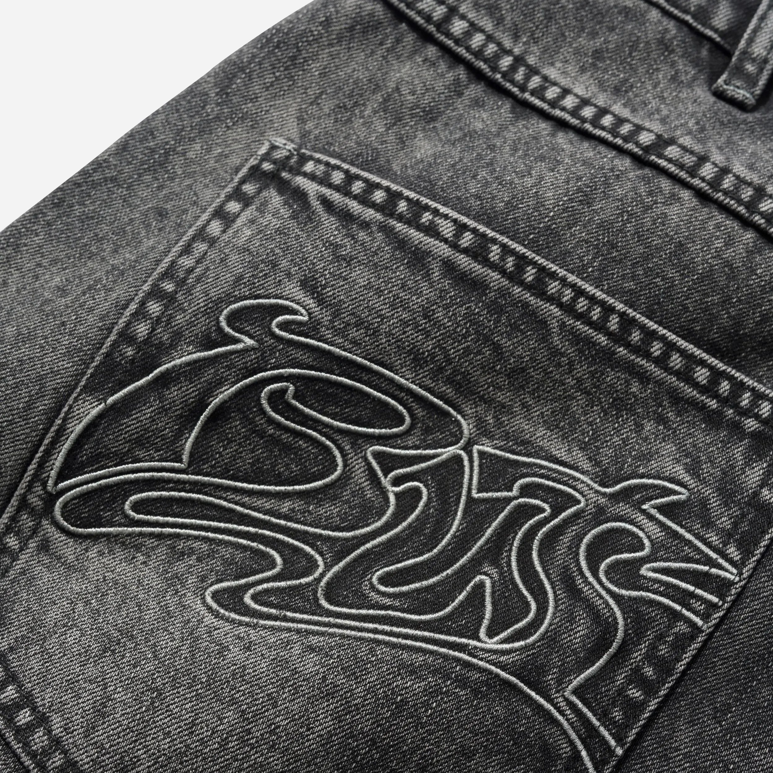 Gros plan sur la broderie de la poche arrière du short Butter Goods.