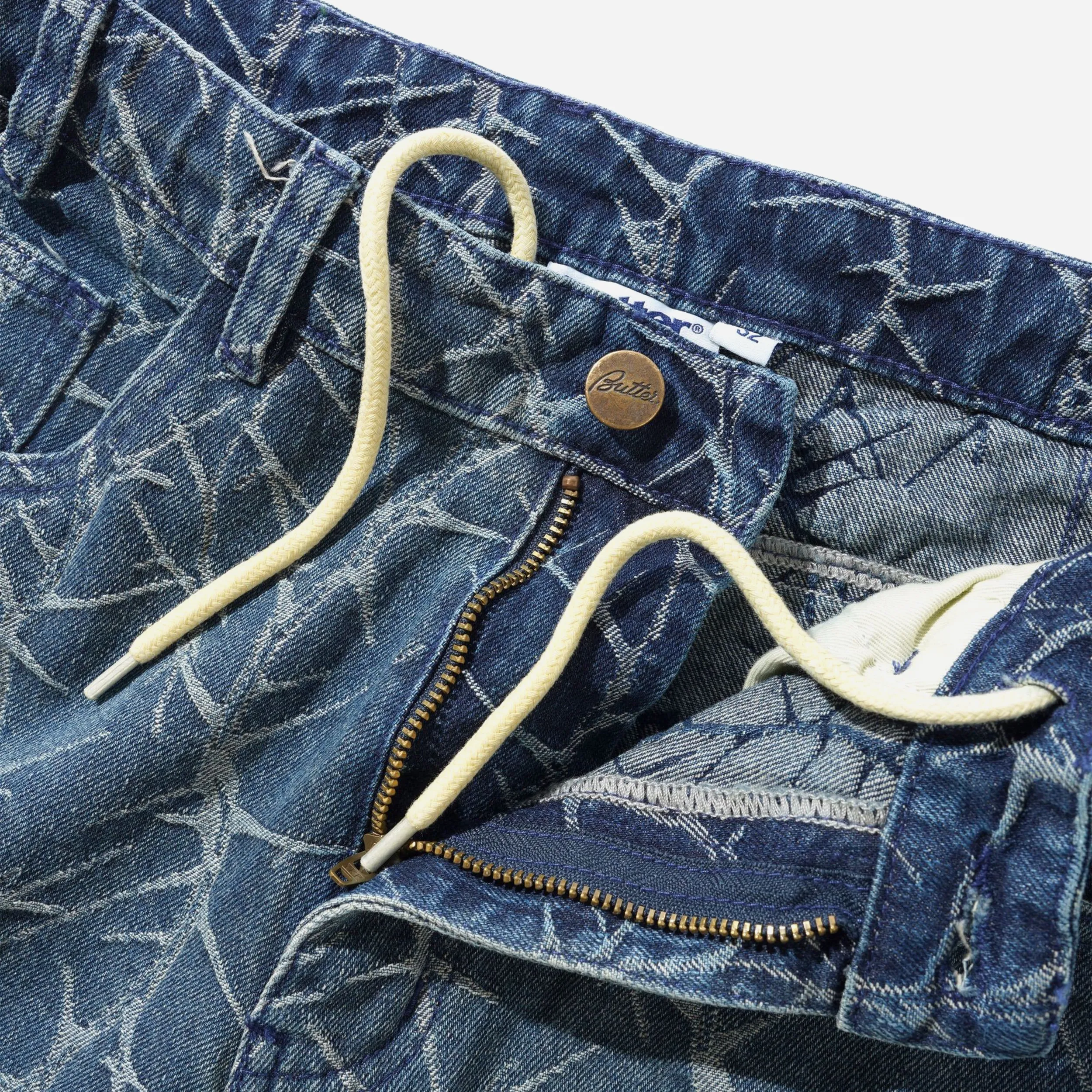 Close-up view of the internal drawstring, zip fly, and engraved button on the Washed Indigo Butter Goods jeans