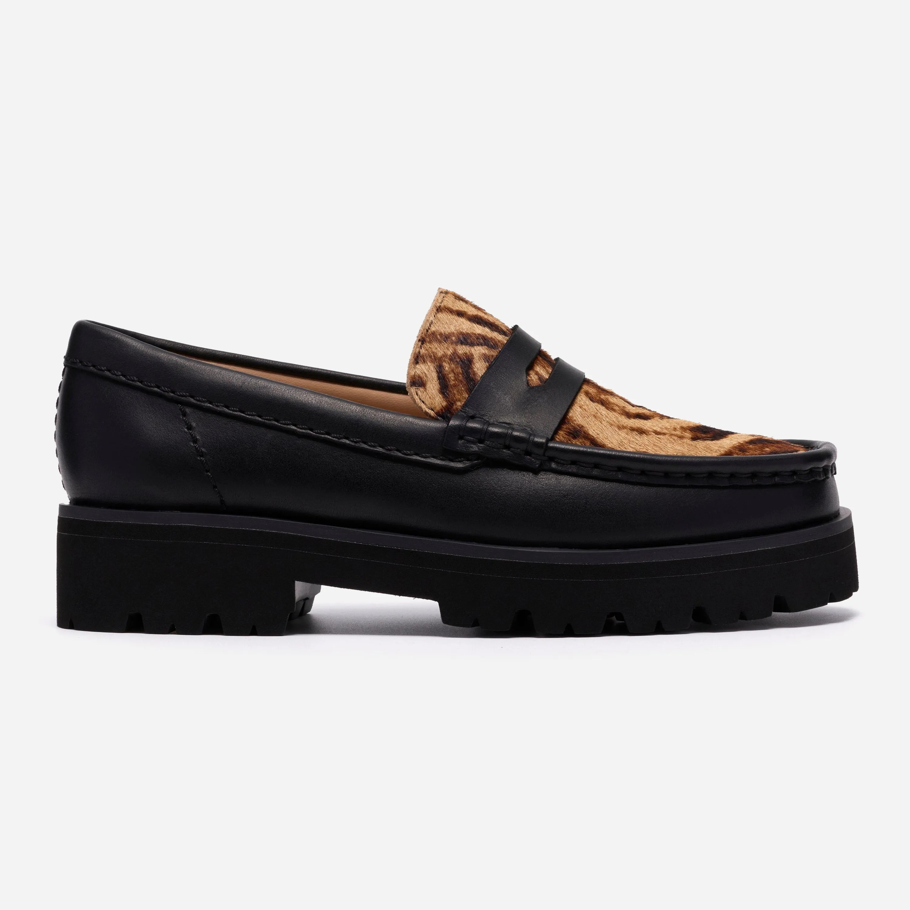 Profil extérieur du mocassin Clarks Yukoner Penny montrant le cuir noir lisse, le plateau en poils léopard et la semelle crantée.