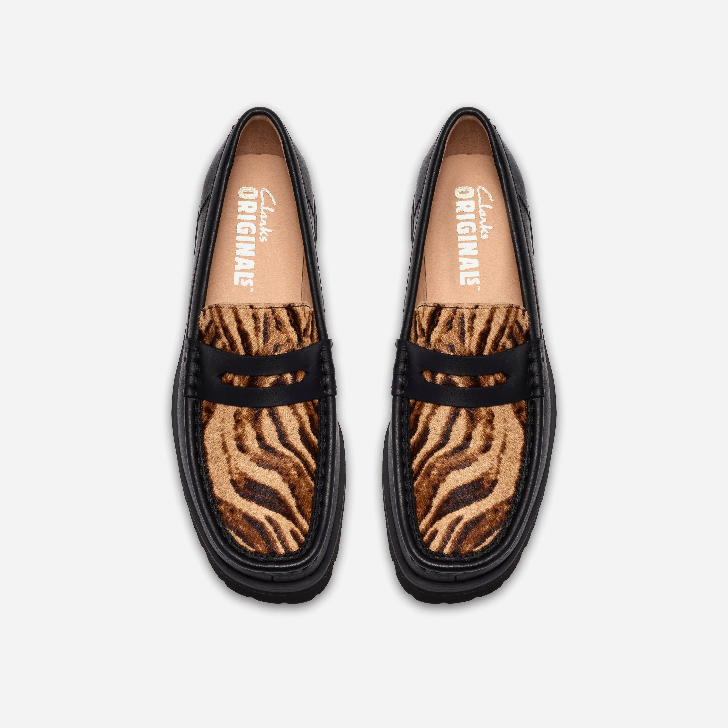 Vue de dessus des chaussures Clarks montrant le motif animalier hair-on, la bride penny noire et la semelle intérieure premium.
