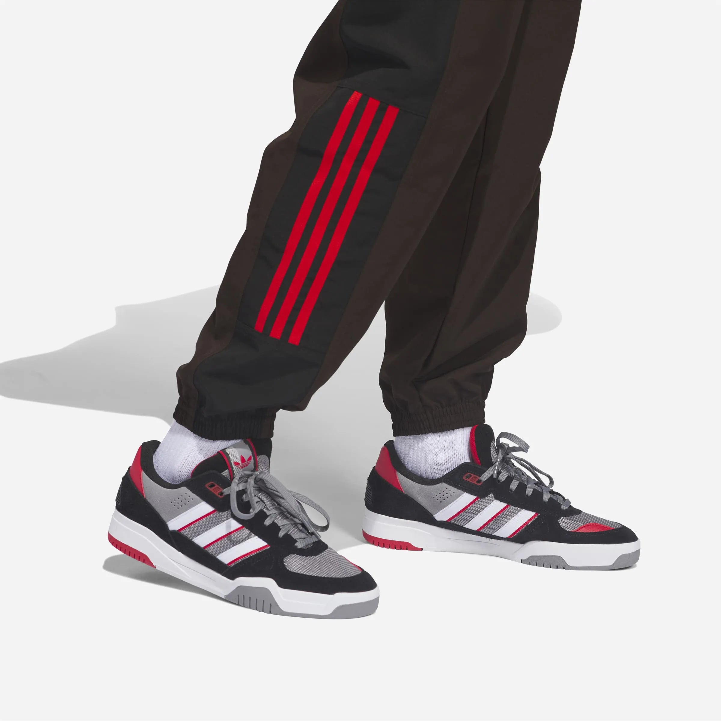 Close up on the three red Adidas stripes on the lower brown pant leg.