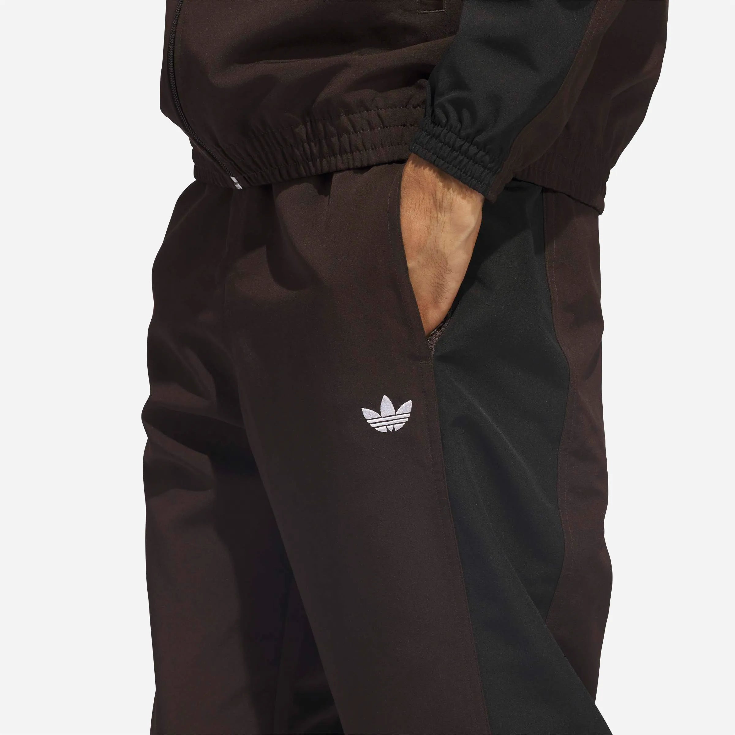 Detail of side pocket and white Trefoil logo on brown background.