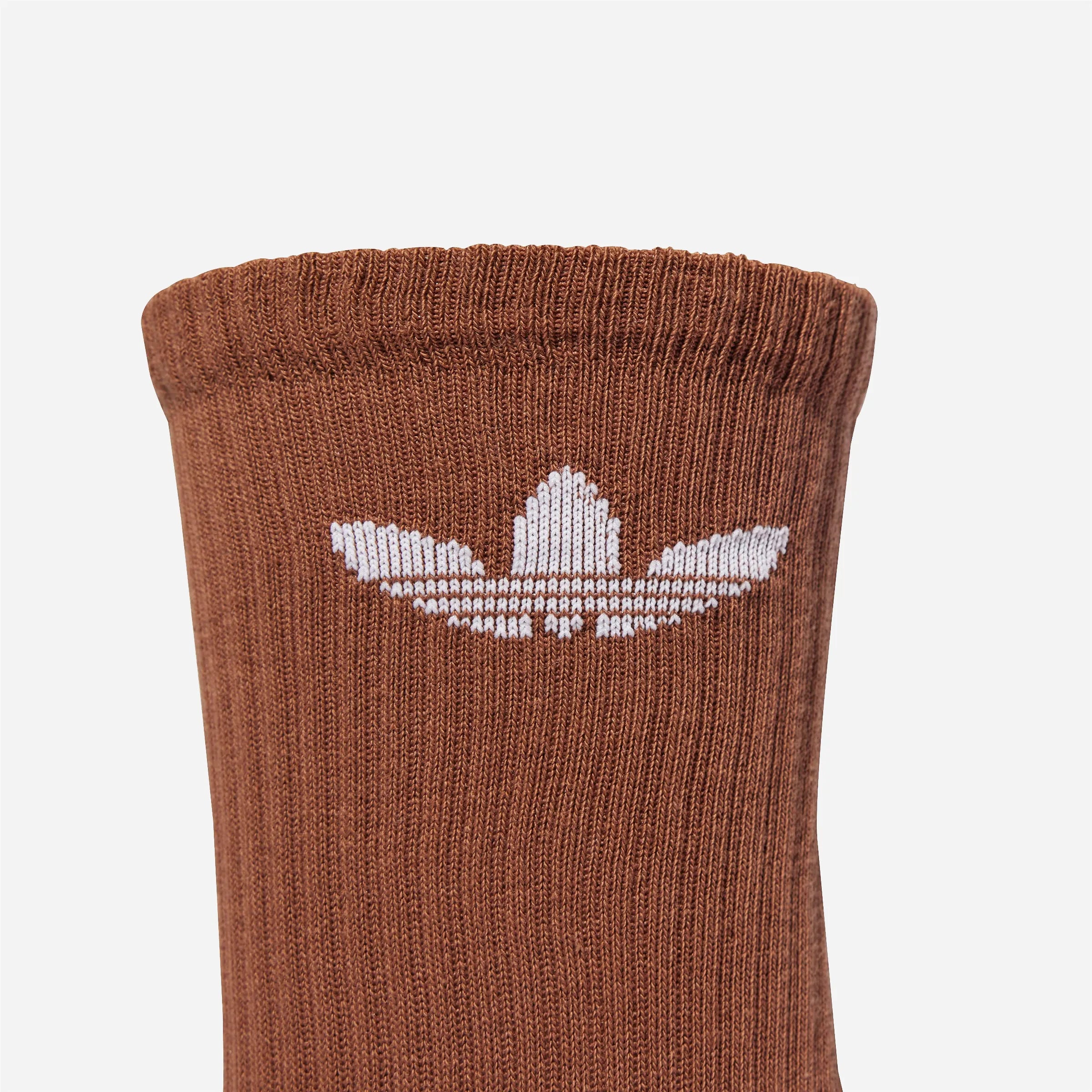 Close-up of white Adidas Trefoil logo on brown ribbed sock.
