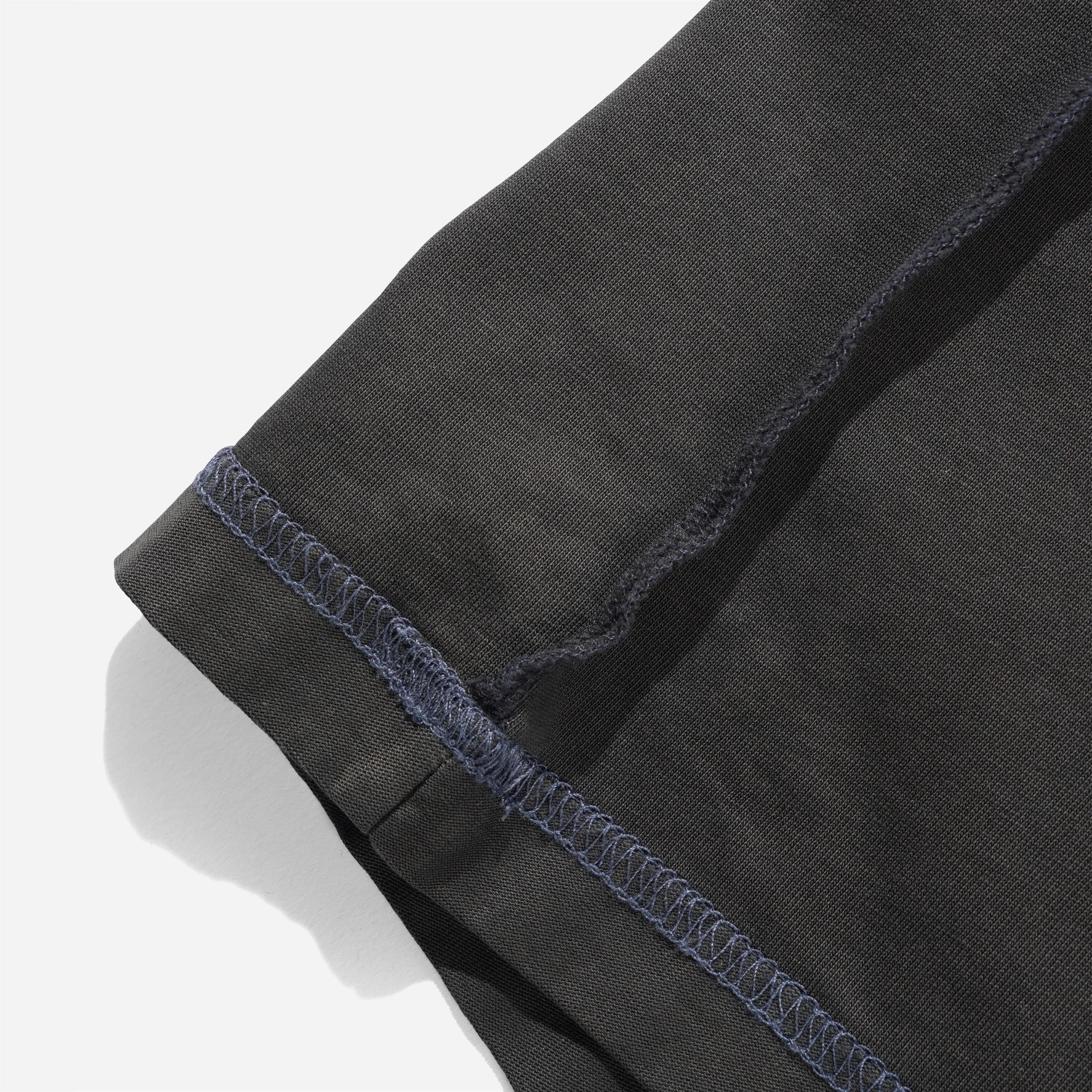 Détail de l'ourlet et des surpiqûres contrastantes du t-shirt Inside Out Washed Black montrant la texture du coton 230g.