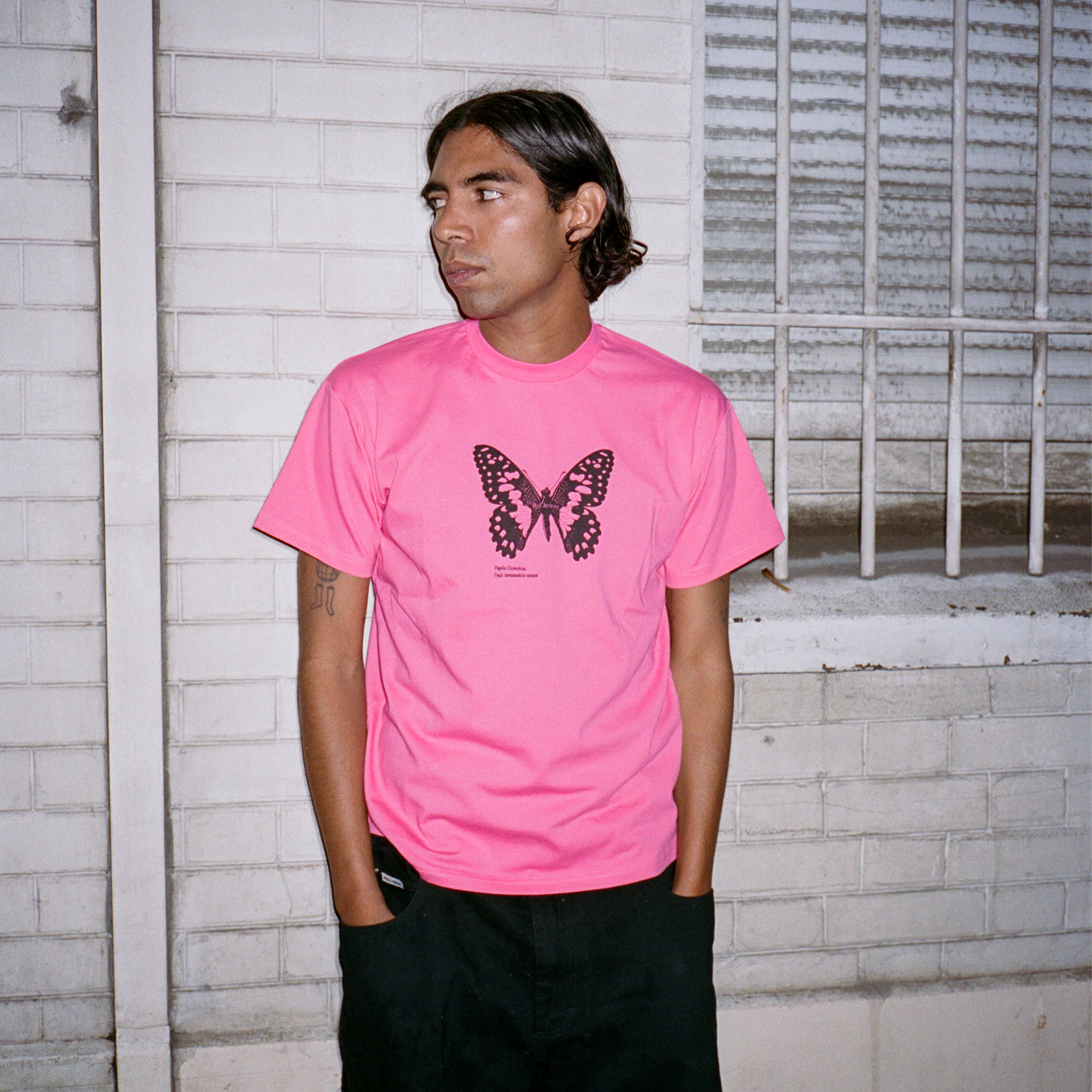 Photo Lookbook portée du T-shirt à manches courtes rose vif de la marque Bye Jeremy, modèle Butterfly Tee, avec un grand papillon noir.