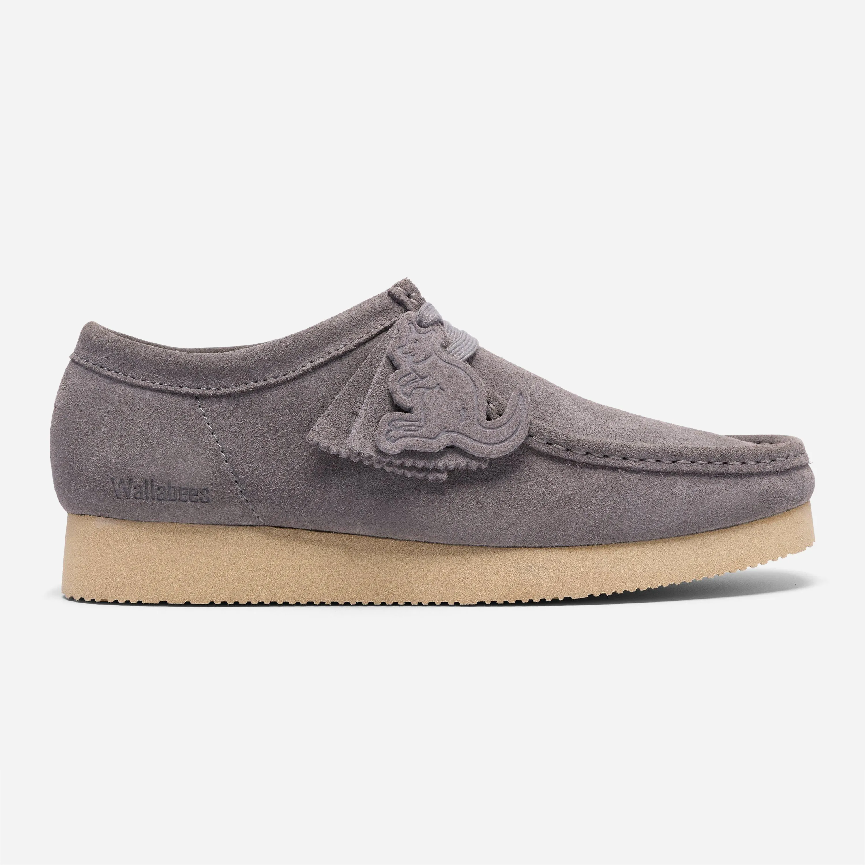 Profil extérieur de la chaussure Clarks Wallabee grise montrant les badges exclusifs en forme de kangourou et la semelle Vibram.