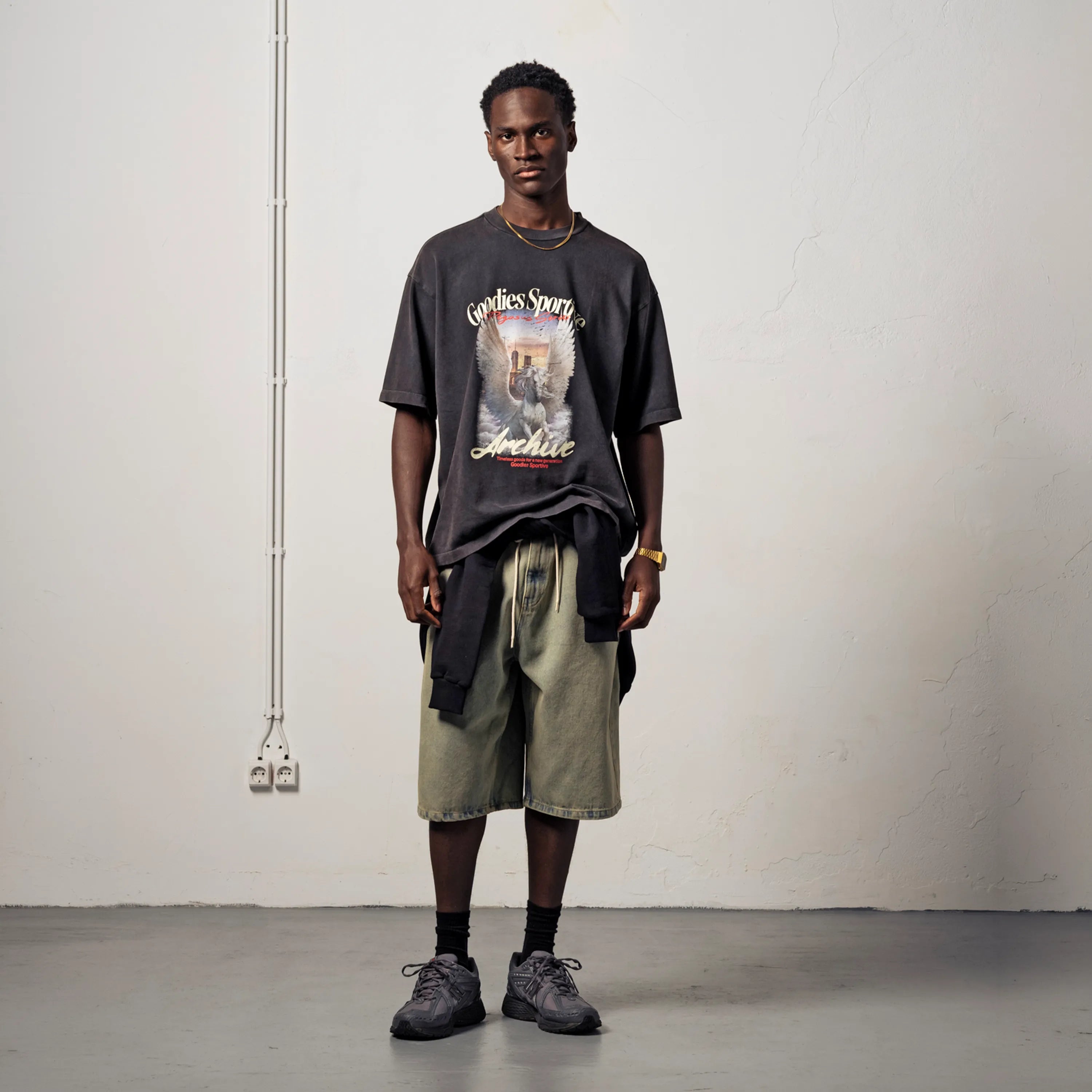 Men's streetwear look with an oversized black graphic T-shirt and denim shorts.