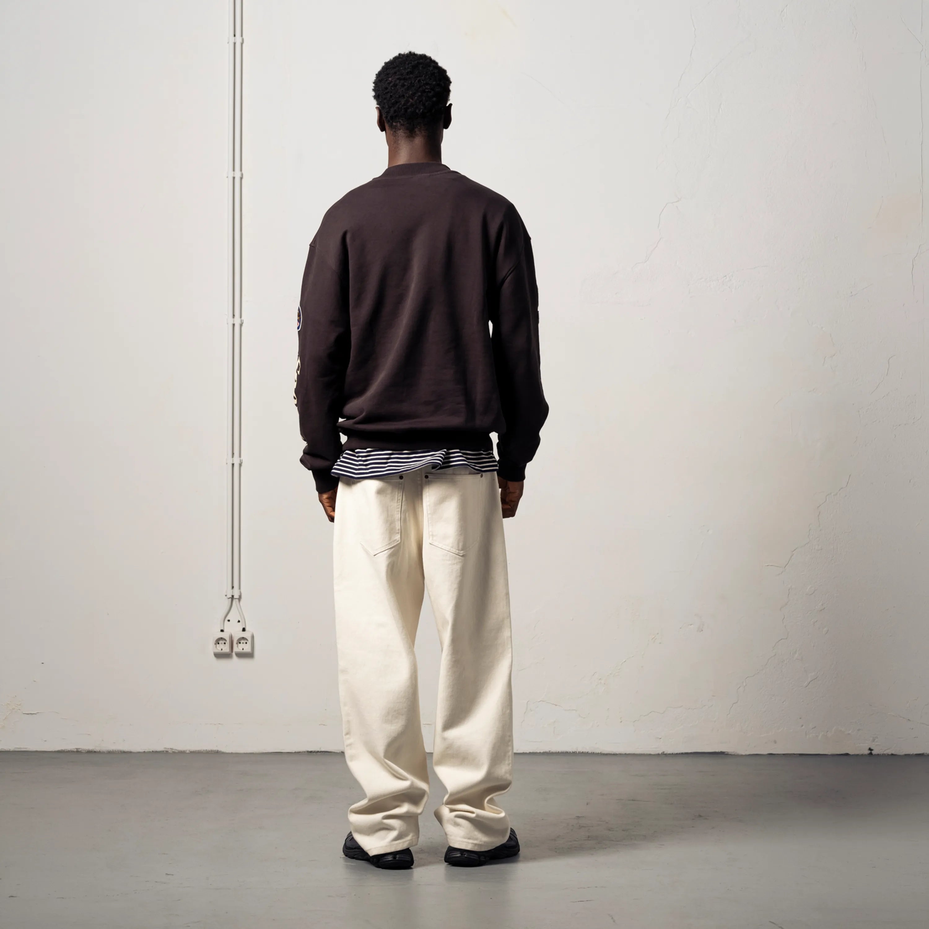 Silhouette of a man's back wearing a thick black Goodies Sportive sweatshirt.