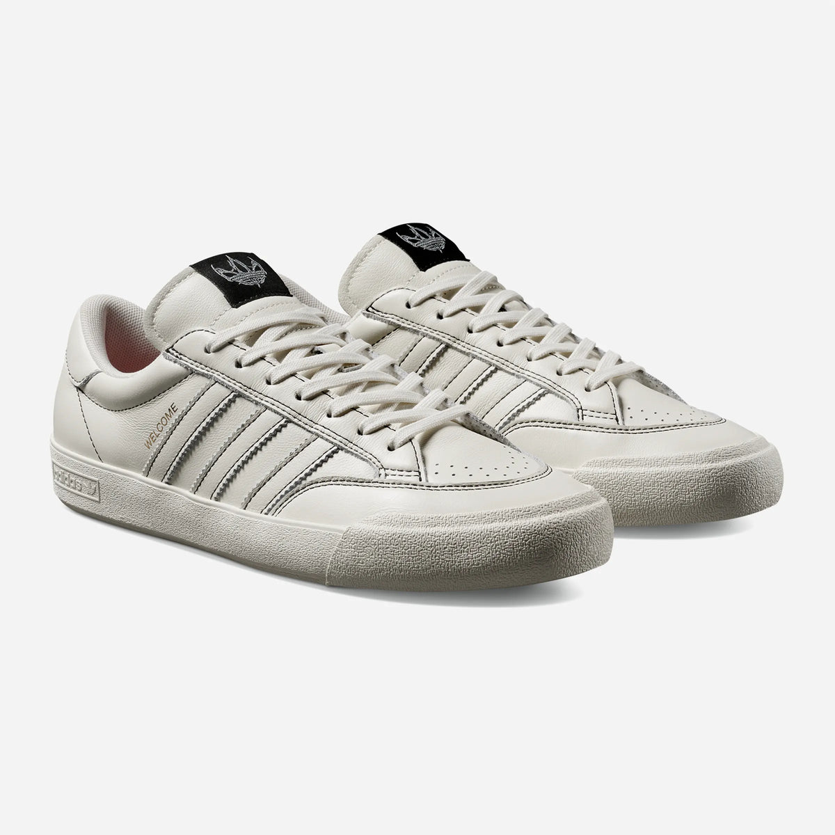 adidas x Welcome Skateboard Nora White White Black, sneaker skate basse en cuir blanc cassé avec bandes dentelées et coutures noires, vue de trois quarts
