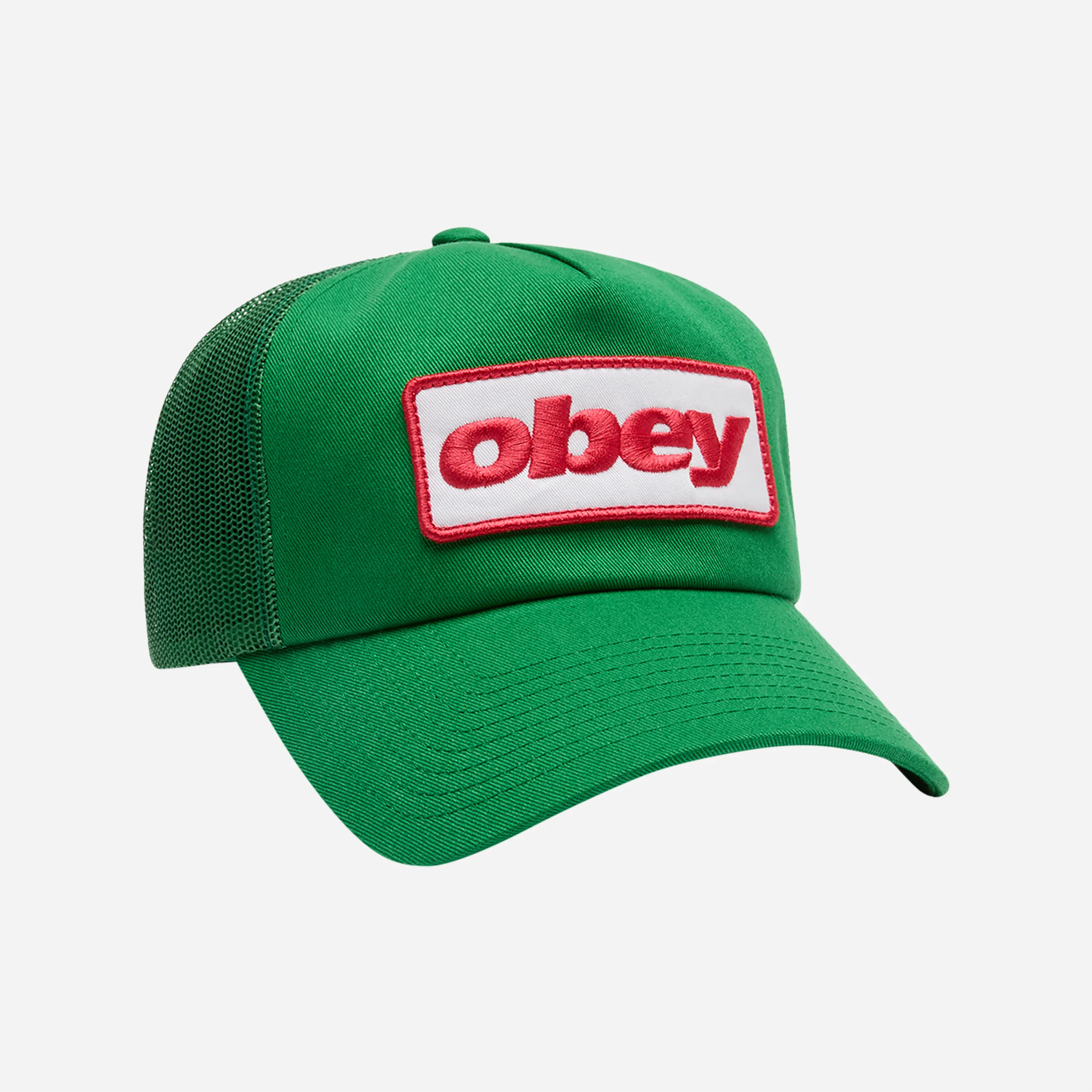 Vue de trois quarts de la casquette Obey Ranch Trucker coloris Jolly Green, mettant en évidence le filet arrière et le large patch logo rouge et blanc.