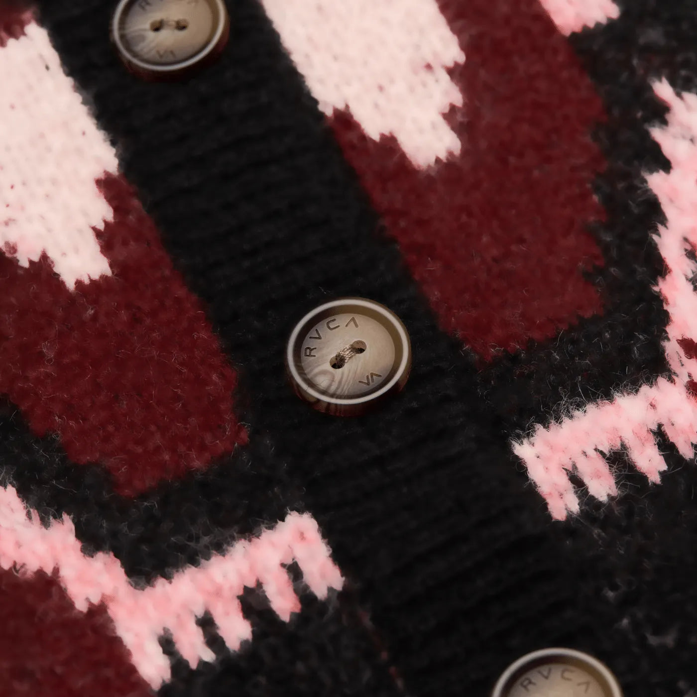 Gros plan sur les boutons gravés et le motif jacquard du cardigan RVCA Fairisle.