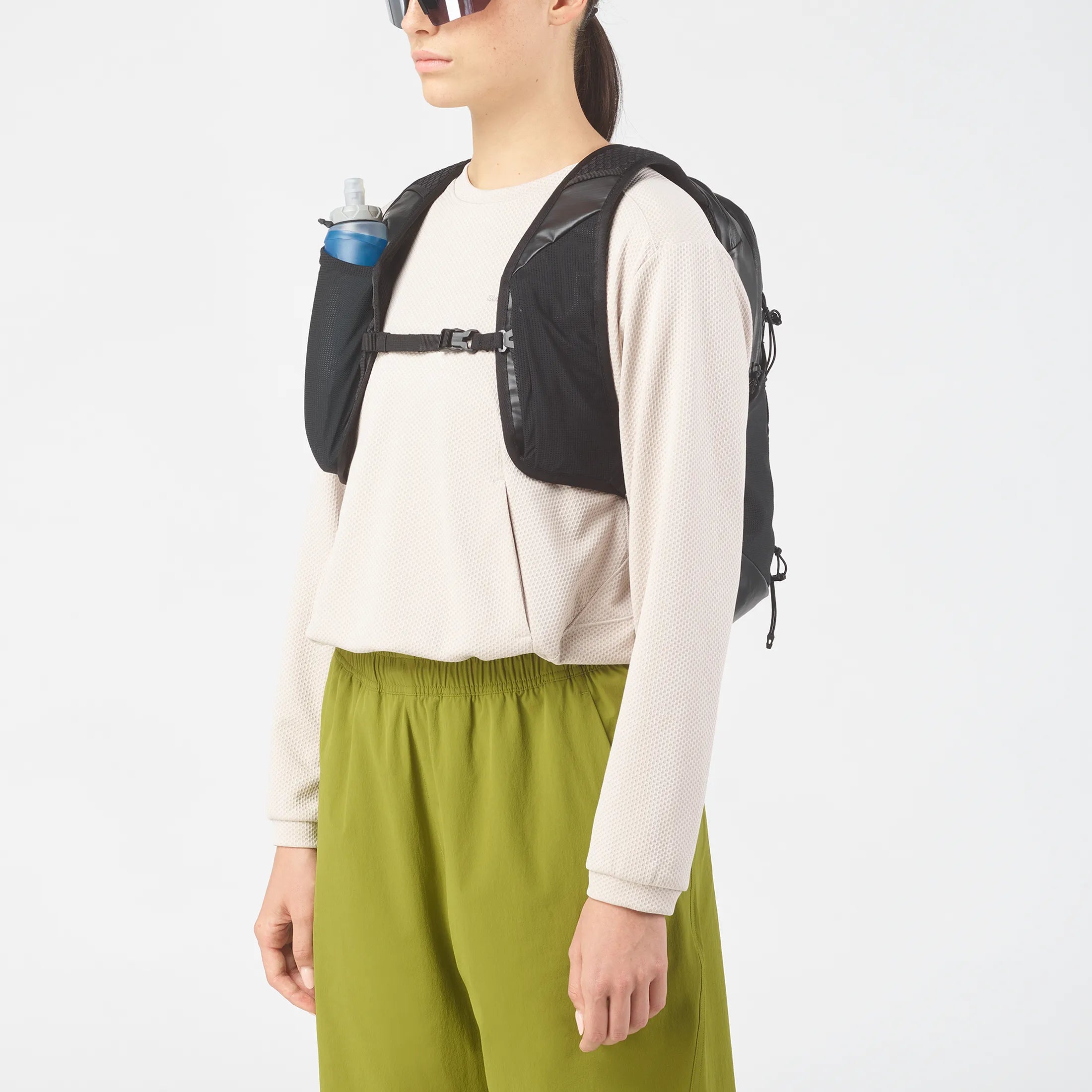 Femme portant sac Salomon avec poche pour gourde flasque sur bretelle.