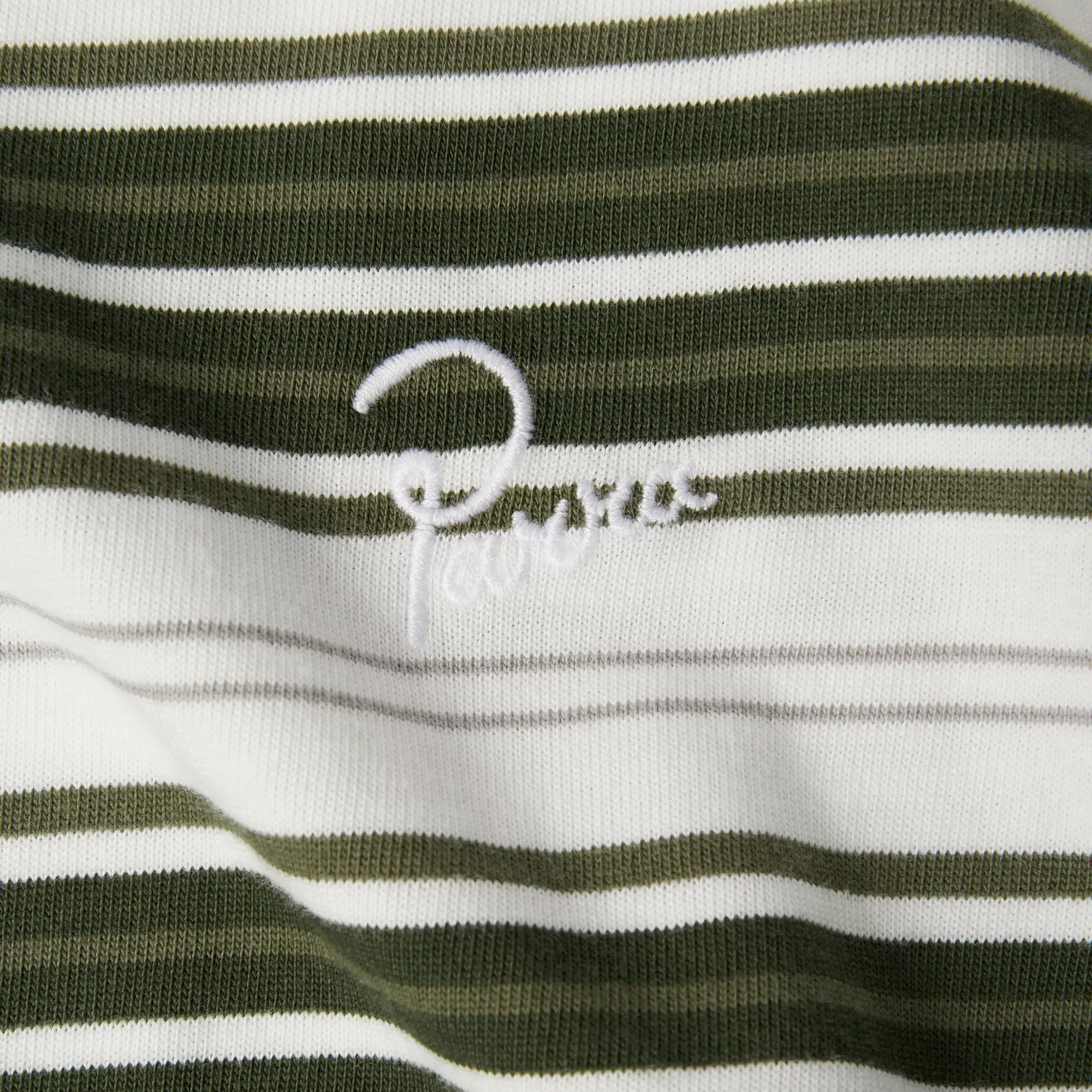 Gros plan sur la broderie du logo Signature sur le t-shirt Parra vert.